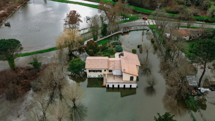 Veduta aerea di una casa isolata circondata dall&#39;acqua a causa di un&#39;alluvione in una zona rurale.