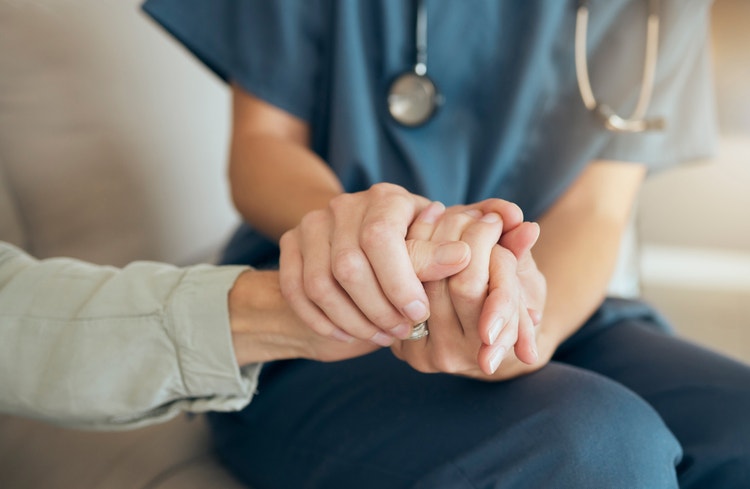 Operatore sanitario che stringe la mano di una paziente