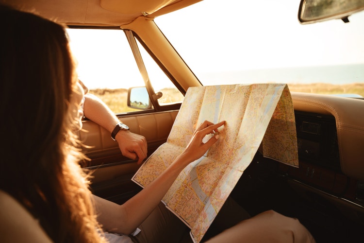 Donna seduta in auto che consulta una mappa durante un viaggio