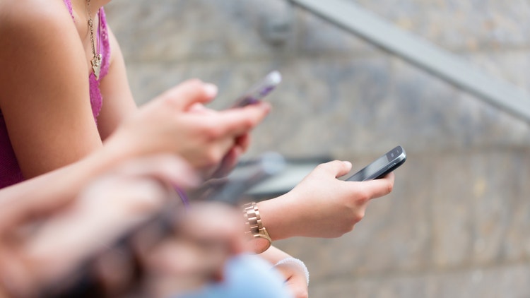 Dettaglio di diverse persone sedute all&#39;aperto che utilizzano i propri smartphone contemporaneamente.
