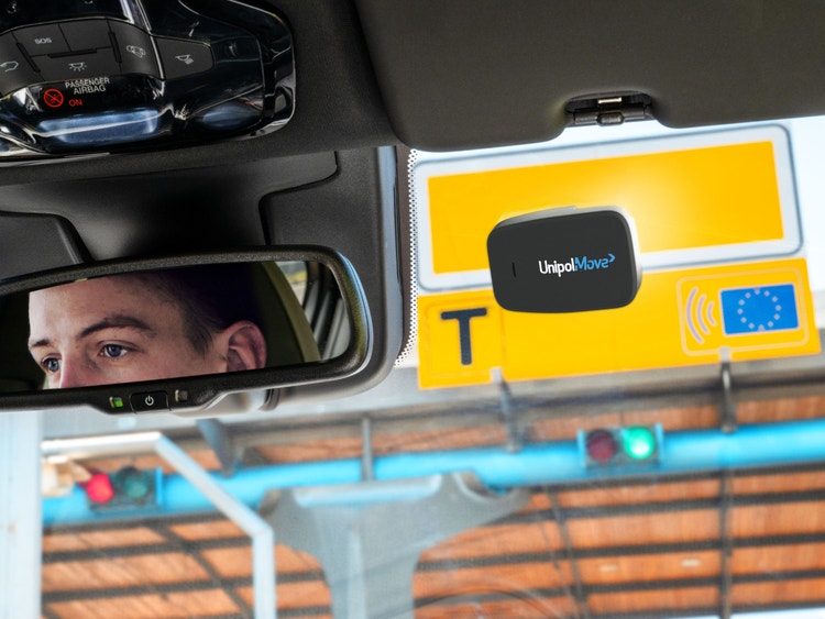 Dispositivo UnipolMove installato sul parabrezza di un&#39;auto che attraversa un casello autostradale.